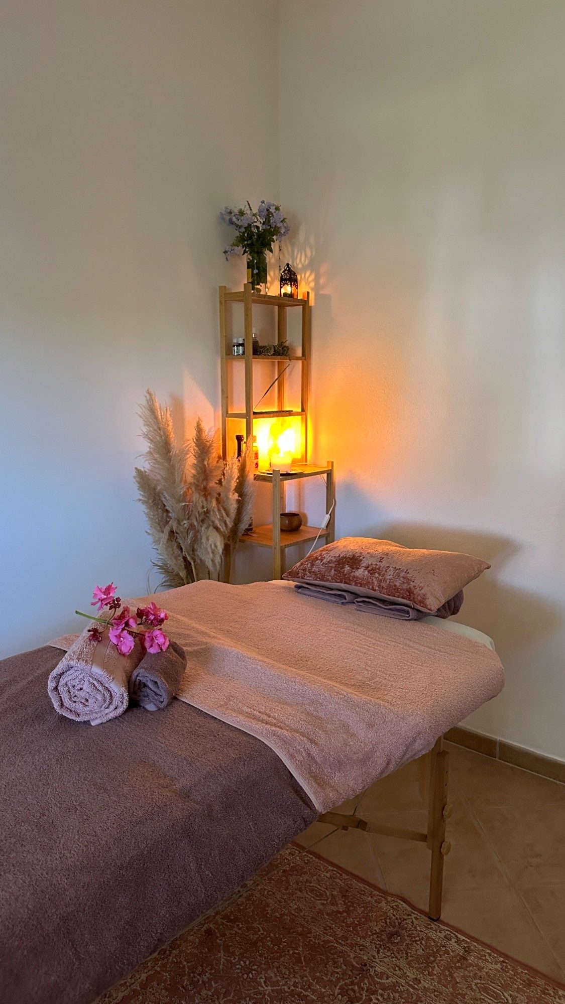 The massage room: massage table with folded towels and orchids, pampas grass and candlelight