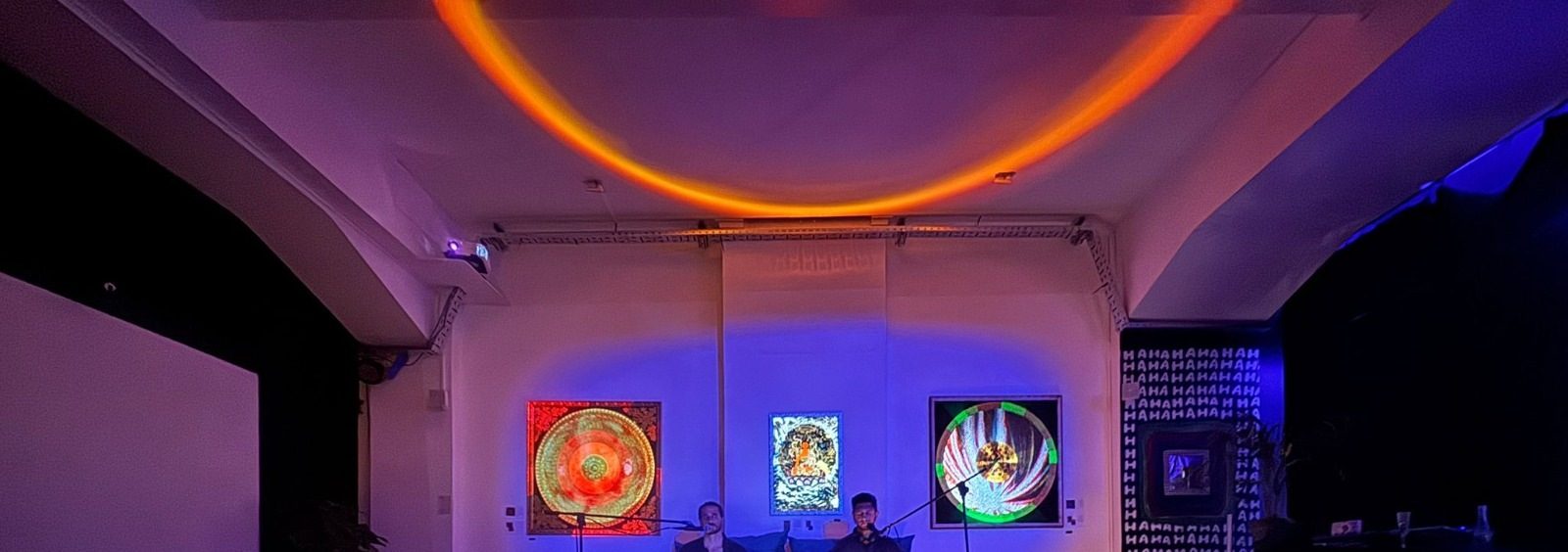 An Alchemy Rewire breath session space lit in violet and orange, with artworks on the wall