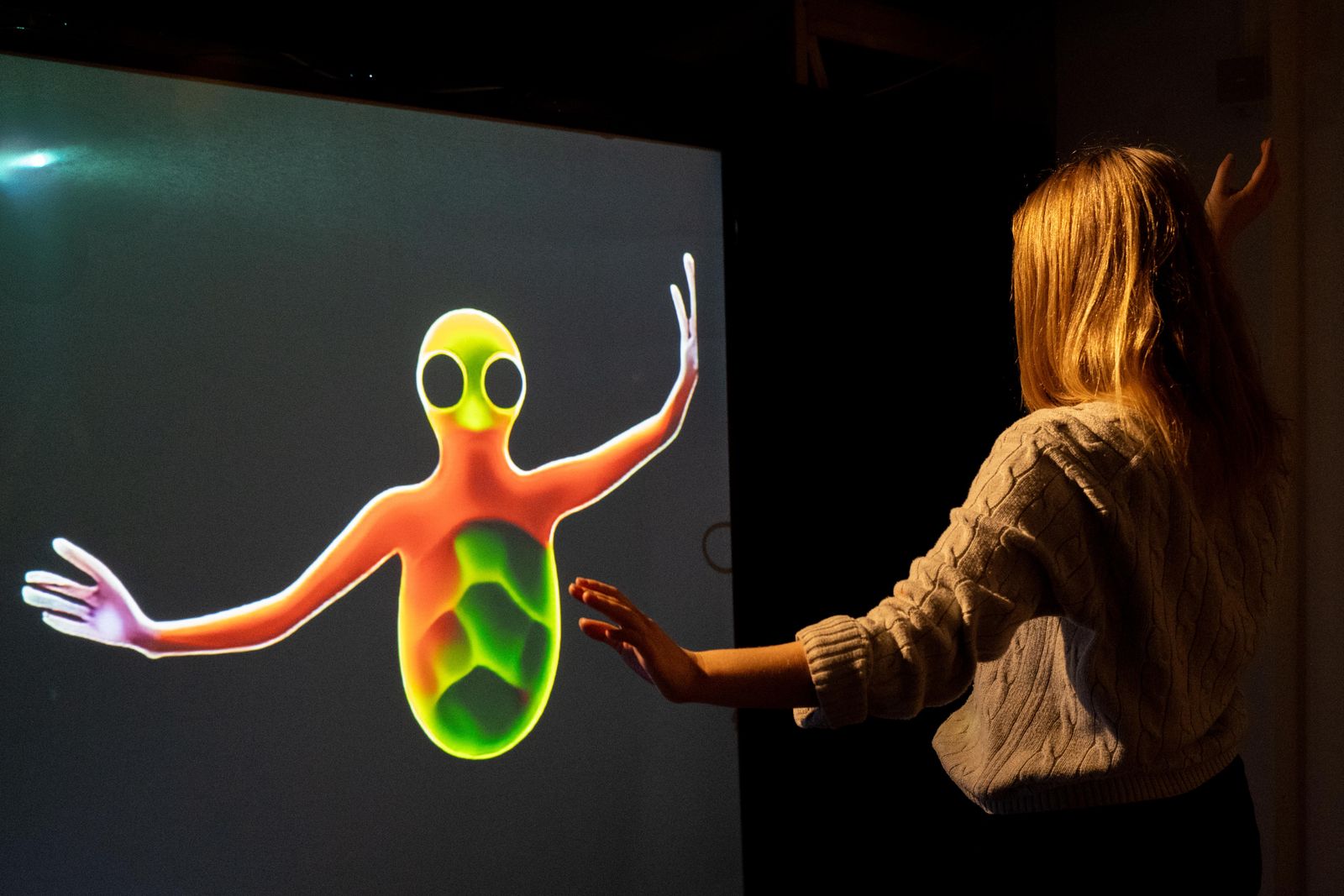 A woman interacting with a large projected figure on the Magic Mirror
