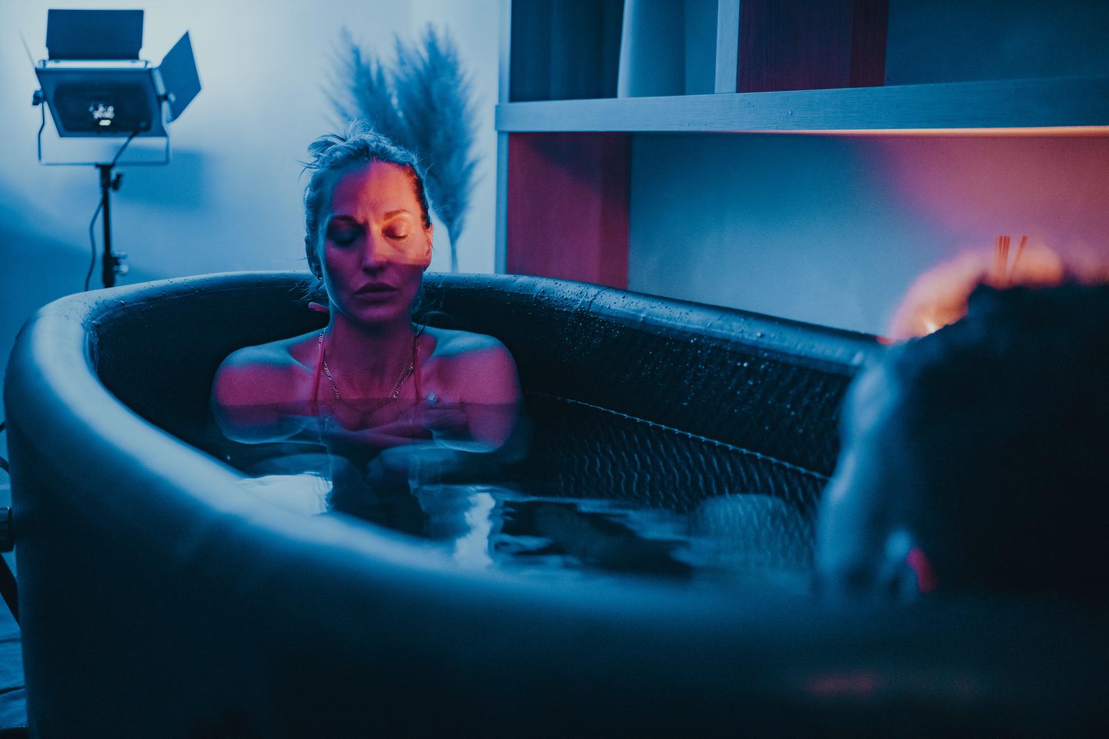 A participant in an ice bath under blue light