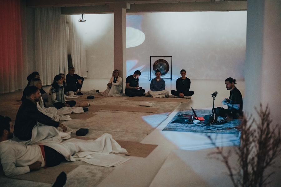 A gong and sound instruments set in a white room with seated guests